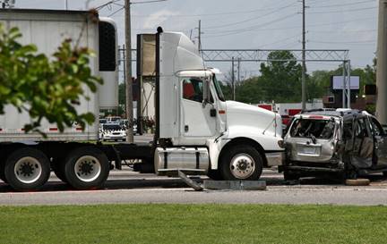 This image shows the aftermath of a truck accident. A large white semi-truck is stopped